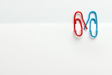 Lovely couple of paper clips hand in hand on white paper for valentines day theme