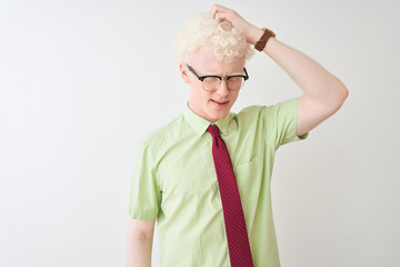 Young albino businessman wearing shirt and tie standing over isolated white background confuse and wonder about question. Uncertain with doubt, thinking with hand on head. Pensive concept.