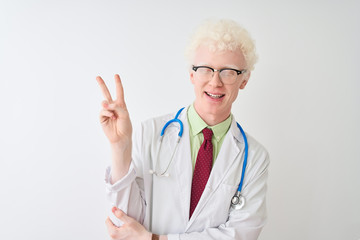 Young albino doctor man wearing stethoscope standing over isolated white background smiling with happy face winking at the camera doing victory sign. Number two.