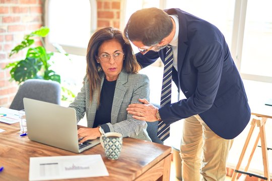 Two middle age business workers working together. Woman suffering sexual harassment at the office