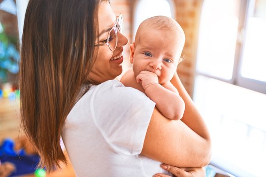 Young beautifull woman and her baby standing at home. Mother holding and hugging newborn