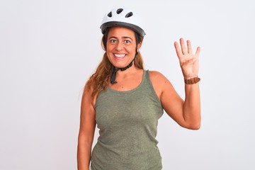 Middle age mature cyclist woman wearing safety helmet over isolated background showing and pointing up with fingers number four while smiling confident and happy.