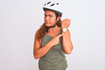Middle age mature cyclist woman wearing safety helmet over isolated background In hurry pointing to watch time, impatience, looking at the camera with relaxed expression