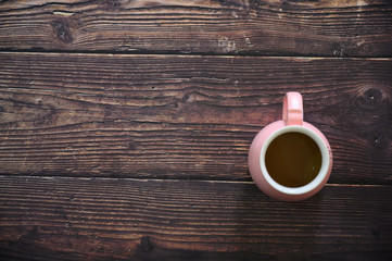 Cappuccino in pink coffee cup on wooden table