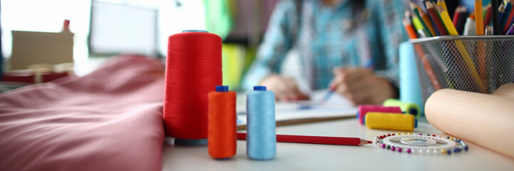 Focus on different threads of various colors used to produce high quality clothes and textile fabric. Strands made of wool prepared for work. Fashioner workshop concept. Blurred background
