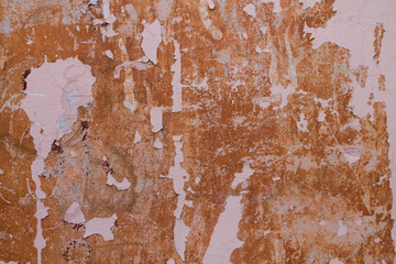 Old weathered painted wall background texture. Red dirty peeled plaster wall with falling off flakes of paint.