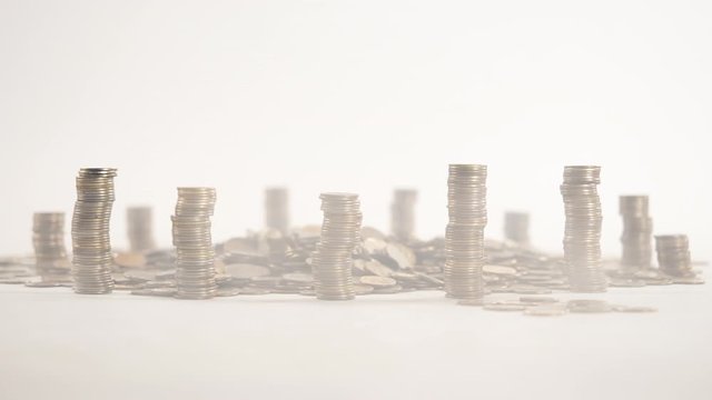 The concept of money. Columns of gold coins in the form of skyscrapers or Stonehenge. Close-up hands make up stacks of coins. Smoke. Garland.