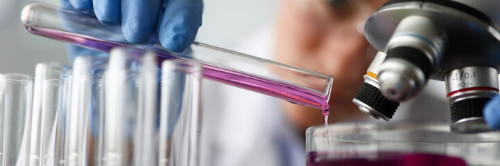 Female chemist holds test tube of glass in hand closeup overflows liquid solution potassium...