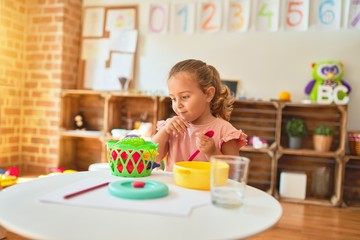 Beautiful blond toddler girl playing  meals using plastic food at kindergarten
