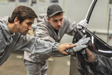 An employee of the quality Department of the car body paint shop provides training on quality...