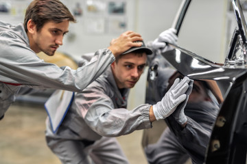 An employee of the quality Department of the car body paint shop provides training on quality control.
