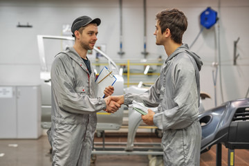 Friendly handshake of two employees of the paint shop.