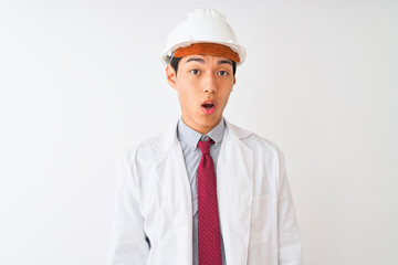 Chinese architect man wearing coat and helmet standing over isolated white background afraid and shocked with surprise expression, fear and excited face.