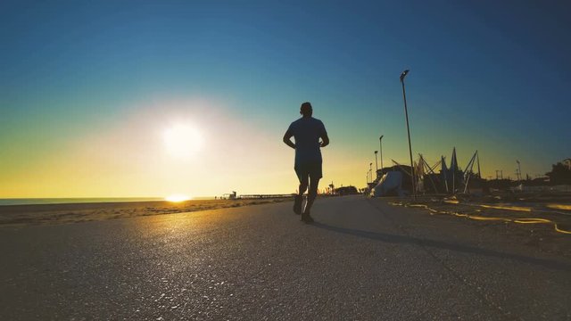 silhouette man running on the California beach at sunset