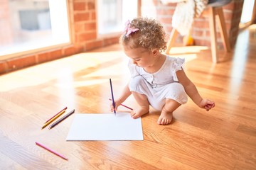 Beautiful caucasian infant playing with toys at colorful playroom. Happy and playful drawing with color pencils at kindergarten.