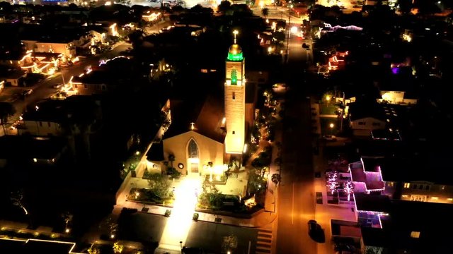 Aerial drone video of American Martyrs Church in Manhattan Beach, CA, USA. Christmas lights of red and green light the bell tower of this impressive catholic church in California.