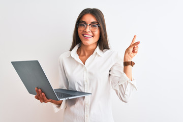 Beautiful businesswoman wearing glasses using laptop over isolated white background very happy pointing with hand and finger to the side