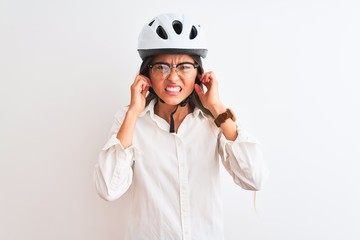 Beautiful businesswoman wearing glasses and bike helmet over isolated white background covering ears with fingers with annoyed expression for the noise of loud music. Deaf concept.