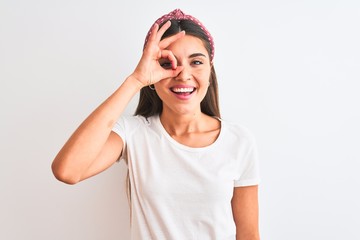 Obraz na płótnie Canvas Young beautiful woman wearing casual t-shirt and diadem over isolated white background doing ok gesture with hand smiling, eye looking through fingers with happy face.