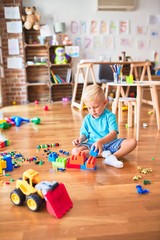 Young caucasian kid playing at kindergarten with toys. Preschooler boy happy at playroom.