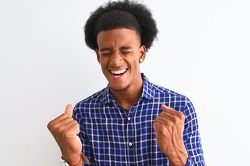 Young african american man wearing casual shirt standing over isolated white background very happy and excited doing winner gesture with arms raised, smiling and screaming for success. Celebration