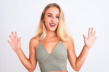 Fototapeta premium Young beautiful woman wearing casual green t-shirt standing over isolated white background showing and pointing up with fingers number ten while smiling confident and happy.