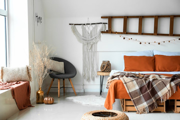 Stylish interior of room with big comfortable bed and autumn decor
