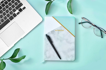 Stylish notebook with laptop and eyeglasses on color background