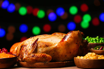 Tasty baked turkey for Thanksgiving day on table against blurred lights