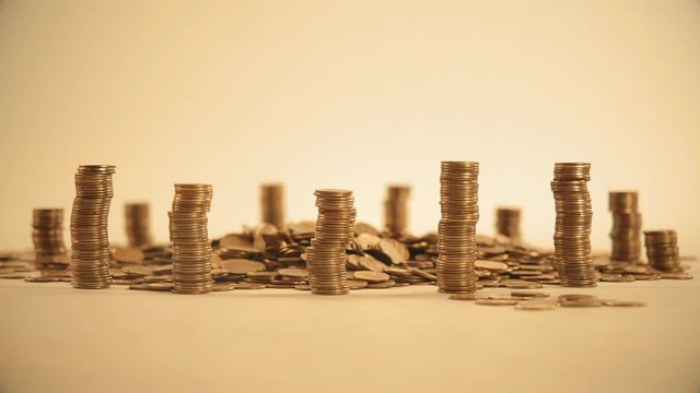 The concept of money. Columns of gold coins in the form of skyscrapers or Stonehenge. Close-up hands make up stacks of coins. Smoke. Garland.