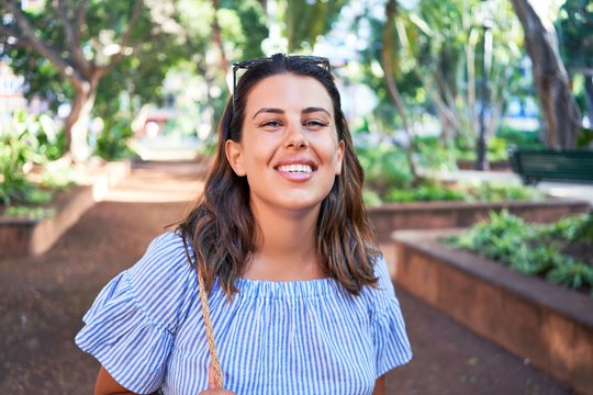 Young beatiful woman smiling happy and cheerful at green park on a sunny day of summer