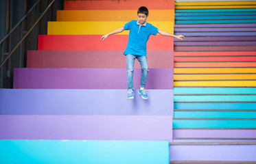 Young boy jumping on the stair rainbow colorful