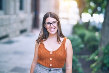 Young beautiful woman smiling happy and confident. Standing with smile on face at the town street