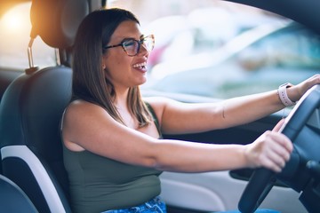 Fototapeta na wymiar Young beautiful woman smiling happy and confident. Sitting with smile on face driving a car