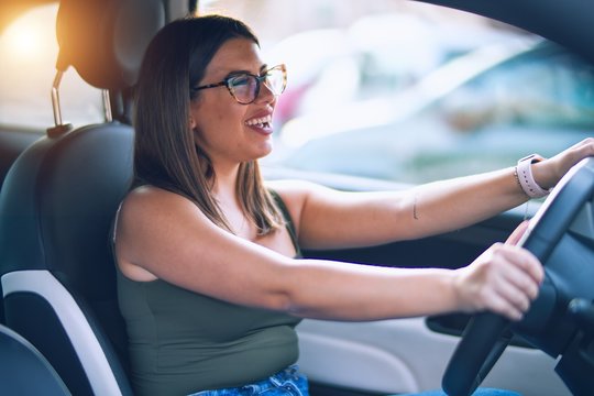 Young beautiful woman smiling happy  and confident. Sitting with smile on face driving a car
