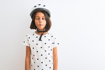 Beautiful child girl wearing security bike helmet standing over isolated white background making fish face with lips, crazy and comical gesture. Funny expression.