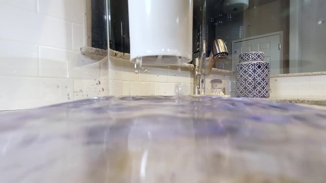 POV from inside clear kitchen pitcher slowly filling with filtered water. Lens partially submerged