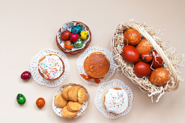 Traditional Easter homemade cakes and wicker basket with colorful Easter eggs on a light...
