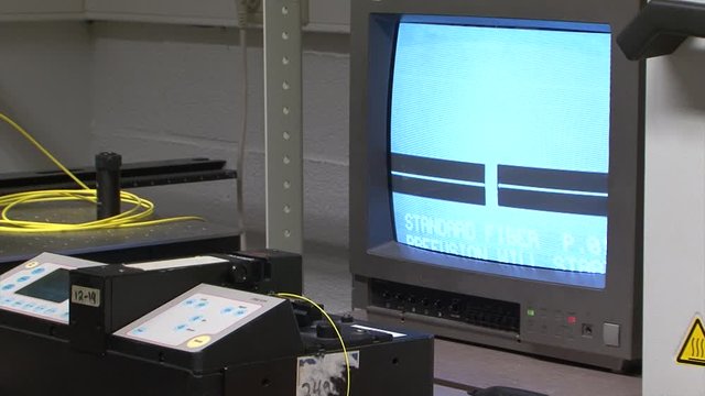 automatic fiber optics cable aligning and splicing in lab with optical fibre machine. Following progress on the monitor.