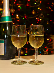 Champaign glasses and champaign bottle in fron of bokeh Christmas tree