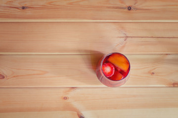 Red wine sangria with fruits in glass on wooden background.