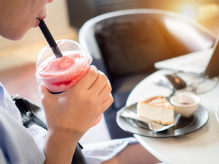 Businesswomen drinking strawberry smoothie fresh and cake sweet dessert  health food  lifestyle between work freelance.Laptop Notebook computer mac is on table wood sofa black color