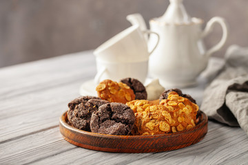 Set of different cookies in a plate and tea on a wooden background.