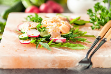 Vegetable salad with fish on pink salt block. Selective focus
