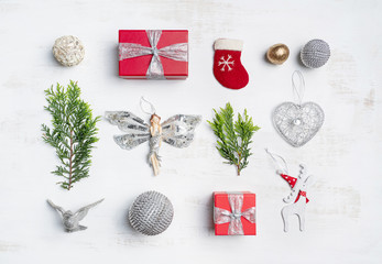 Christmas inspired flat-lay on rustic surface. Gifts, reindeer, angel, ball balls, birds and Christmas tree foliage. In reds, greens, whites, silvers and golds.