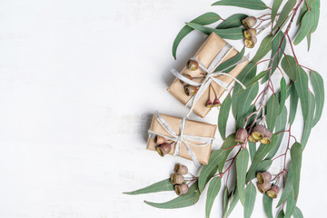 Gifts surrounded by Australian native eucalyptus leaves and gum nuts tied with silver ribbon, on a...