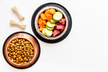 Ingredients of dry feed for dogs - meat, vegetables - near bones on white background top view copy space