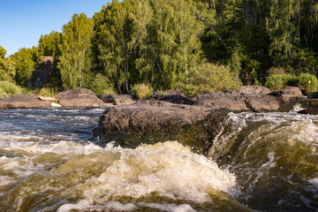 view from a low point on mountain waters seething on the rapids of a swift mountain river