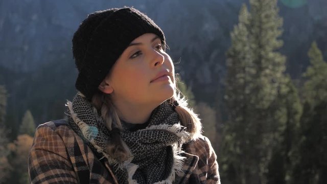 Young tranquil woman sits outdoors enjoying sun on winter morning in Yosemite