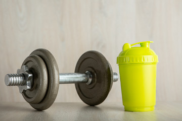 Iron dumbbell and shaker on a wooden floor